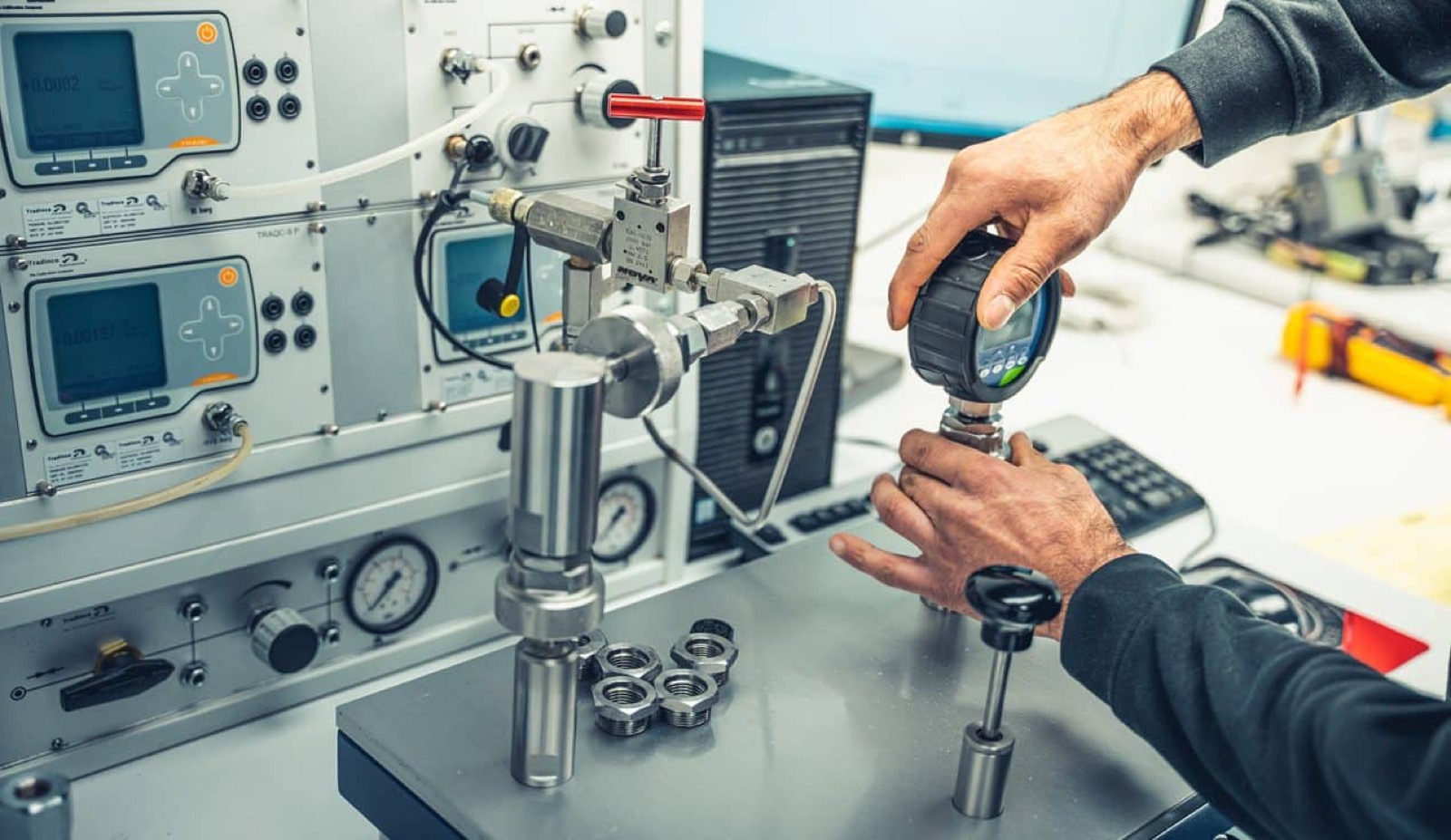 Technician calibrating a digital pressure gauge on a calibration bench